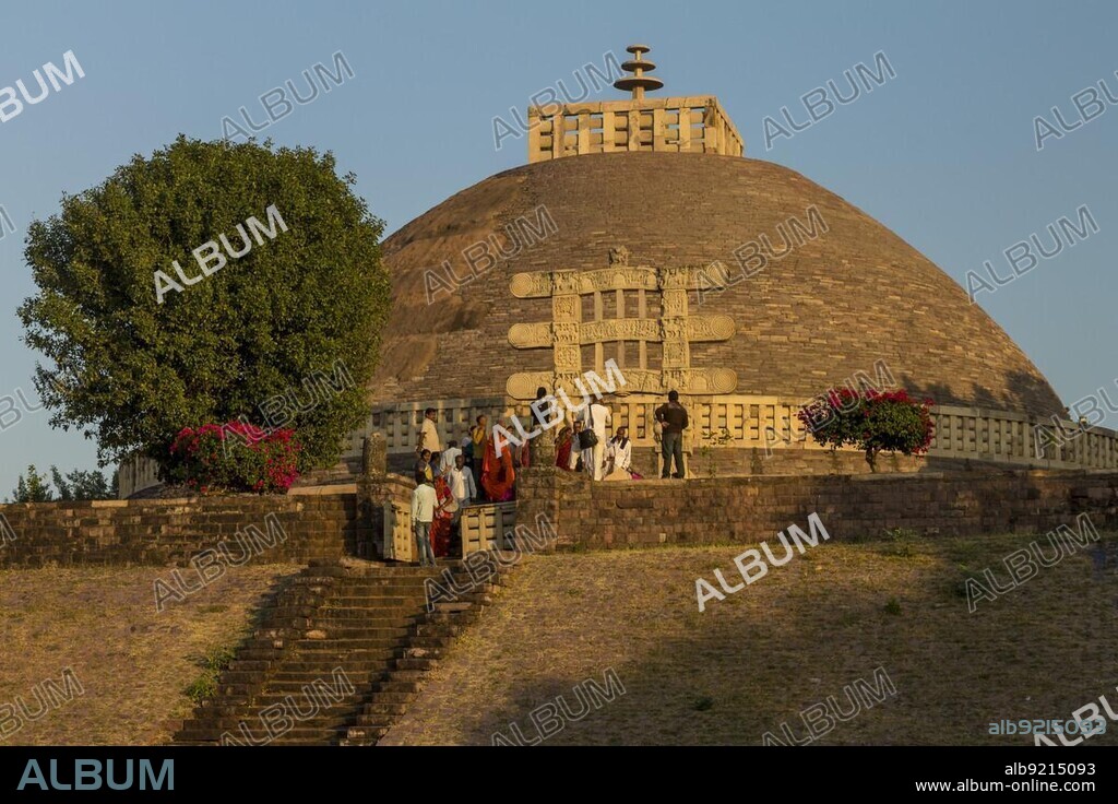 The Great Sanchi Stupa, Stupa 1, general view from the western side, shortly before sunset. Some tourists or pilgrims. Tree. Group of Buddhist Monuments at Sanchi, a monument of Indian Architecture, constructed at the time of ruler Ashoka, Maurya Empire, Indian Subcontinent, A UNESCO World Heritage Site. Sanchi, Madhya Pradesh, India, Asia.