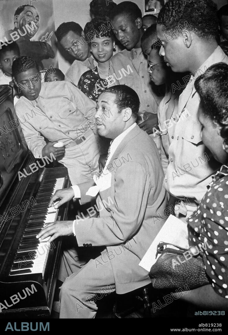 American jazz musician Duke Ellington plays the piano for a group of servicemen and women, Hartford, Connecticut, 1942. Jazz vocalist Joya Sherrill, who sang with Ellington thorughout most of the 1940s, stands at center rear (she wears a pearl neckace). A poster de Ellington is on the wall.