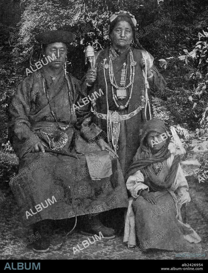 Historical Geography. 1900. India. A family photograph of Sikkim Bhotias of Tibetan origin, displays paternal authority with its formidable whip, motherly piety with a praying-wheel, and juvenile obedience seated humbly beneath. Their gorgeous apparel proclaims this is a wealthy family, for the mother has turquoise earrings and the daughter a jewel-studded charm-box. They are of a patriarchal race, sons bringing their wives to live under paternal roof.