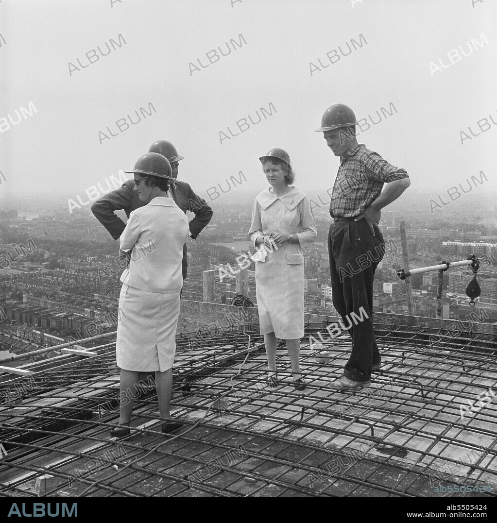 JOHN LAING PLC. Empress State Building, Lillie Road, Earl's Court, Hammersmith and Fulham, London, 03/07/1961. Two women with a construction worker and manager gathered on the roof of Empress State Building, to watch the final concrete pour. Laing built the foundations and the reinforced concrete frame of the building, work began in November 1959 and ran until July 1961. The group were gathered on the roof to the watch the final pour of concrete to complete the project.