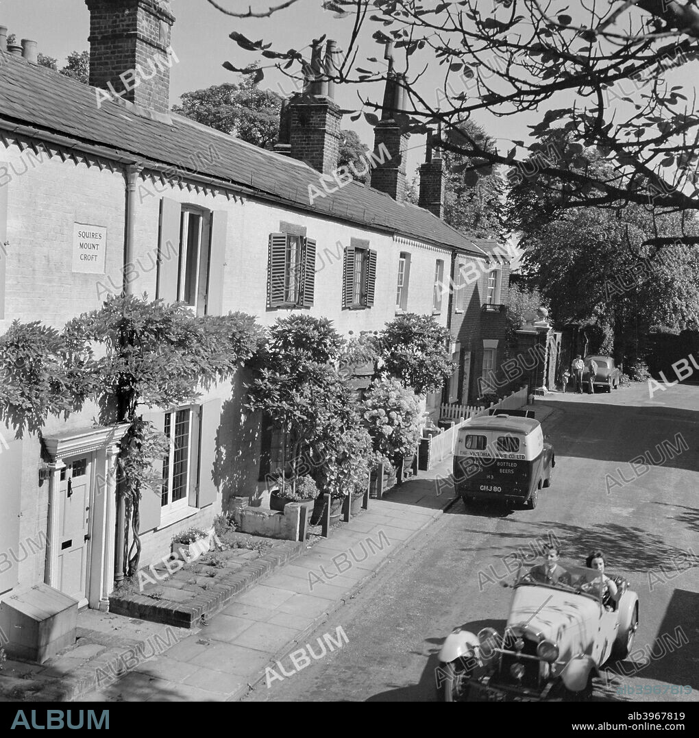 Squires Mount, Hampstead, London, 1962-1964. The exterior of the terrraced cottages of Squires Mount, looking south east from No 1 towards No 5, a Victoria Wine van parked outside and an open-topped sports car driving past.