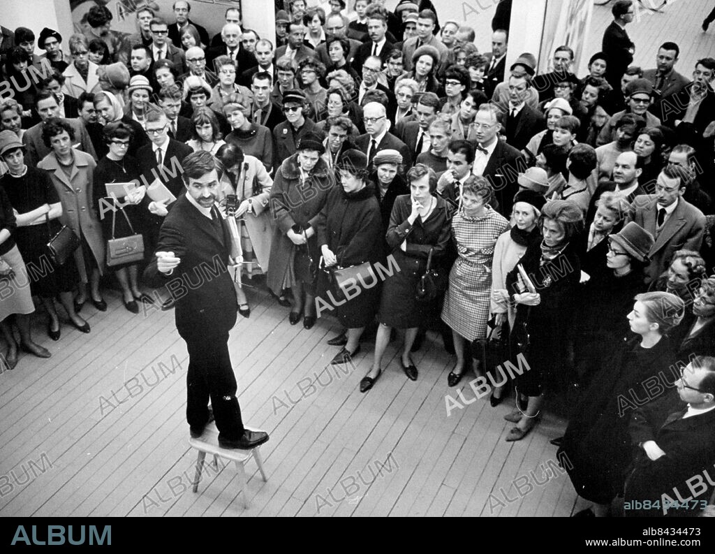 Stockholm 1964-04-03. Carlo Derkert, intendent på Moderna Museet står uppflugen på en pall i samband med en visning . Foto: Ragnhild Haarstad / SvD / TT / kod 12014.