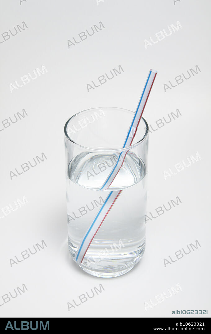 A drinking straw is immersed in a glass of water to demonstrate optical refraction. This illusion is due to the difference in the refractive index between water and air.
