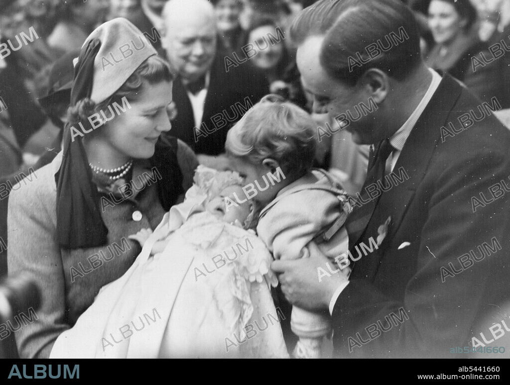 Mr. Churchill's Grandchild Christened -- Mr. Winston Churchill (in background) looks on as little Nicholas Soames kisses his baby sister Emma Mary, who is held by Mrs. Christopher Soames, formerly Miss Mary Churchill. Captain Soames is soon with his wife. Mr. Winston Churchill paid a visit to this Sussex village to attend the christening ceremony of his sixth grandchild, Emma Mary, infant daughter of Mr. and Mrs. Churchill's daughter, Mary, wife of Captain Christopher Soames. Captain Soames is prospective Parliamentary candidate of Bedford. November 6, 1949.