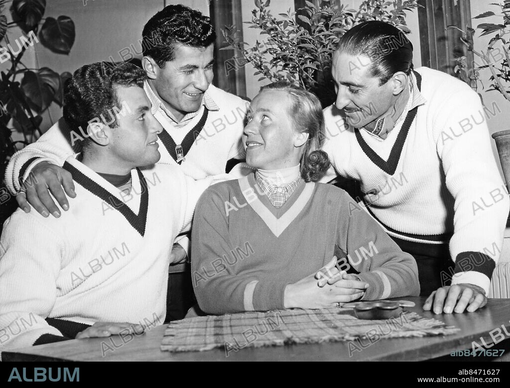 ÅRE 1954-02-27.. VM på skidor ska börja i Åre. Här ses, dan före dan, den svenska slalomåkerskan Ingrid Englund koppla av omgiven av de libanesiska skidåkarna Simon Khoury-Saade, Ibrahim Gaegea och Michel Samen.. Foto: Owe Sjöblom / AB Text & Bilder / SVT / Kod: 5600. Mapp: Skid-V.M. (de alpina grenarna) i Åre 1954. Kvartett Vänner V-ringad tröja.