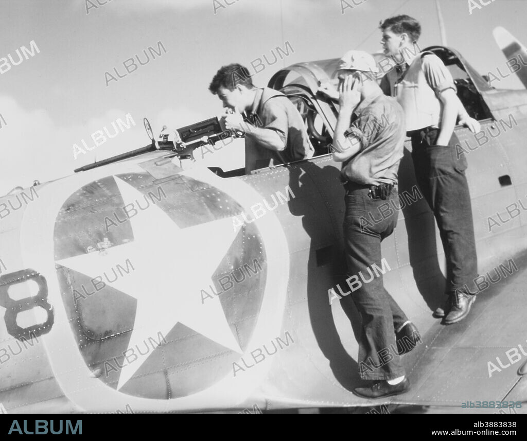 November 1942 - A radioman gunner test fires his twin .30 caliber machine guns on the Douglas SBD-3 Dauntless scout bomber during Operation Torch. Two other sailors are observing, with one slightly protecting his hearing by holding a finger in one ear.