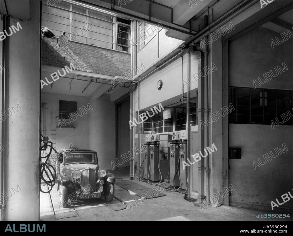 The garage of the Stepney Carrier Co Ltd at 94-100 St John Street, Islington, London, c1935. A car is parked on a ramp, and petrol pumps can be seen to the right.