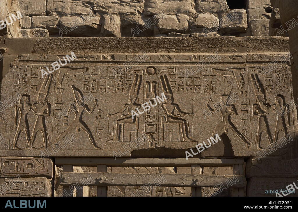 ARTE EGIPCIO. Detalles de los relieves que decoran la CAPILLA dedicada a la TRIADA TEBANA formada por los dioses AMON, MUT Y KHONSU (JONSU). En la zona central, el diós Amón con gran casco cubierto de dos grandes plumas y barba postiza sentado en el trono. Lado septentrional del PRIMER PATIO DE RAMSES II. TEMPLO DE LUXOR. EGIPTO. IMPERIO NUEVO.
