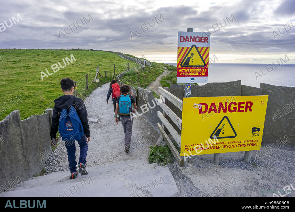 hikers and danger sign, Cliffs of Moher, The Burren, County Clare, Ireland, United Kingdom.