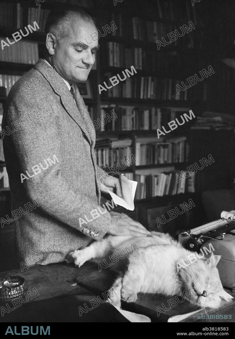 Alberto Moravia (1907-1990) in his study with a Persian cat. Moravia was an Italian writer (born Alberto Pincherle) who had tuberculosis as a child, forcing him to have study at home and to have lots of time to do so. At the age of 22, he wrote "The Time of Indifference", a novel criticizing fascism. He did not like Mussolini and was on the run during the war because of harassment from the government, forcing him to write under the pseudonym Moravia.