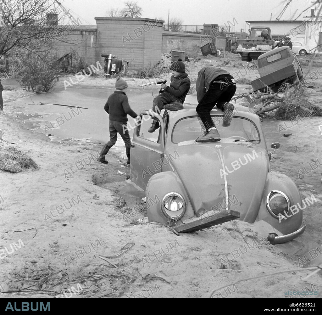 A group of children plays in the disaster area in Hamburg-Wilhelmsburg on the roof of a destroyed VW Kaefer on the 28th of February in 1962. In the background, clearing-up operations after the devestating storm tide take place. All in all, 300 people died in the storm tide, several thousand people became homeless. Especially Wilhelmsburg, a part of Hamburg, was affected. 17/02/1962