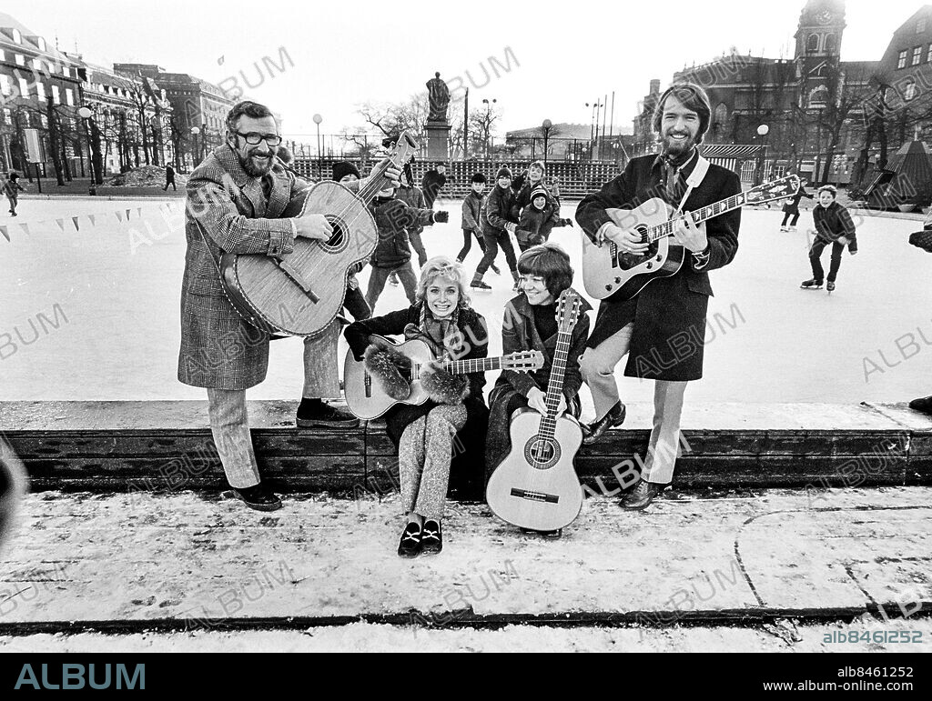STOCKHOLM 1971-01-12.. Family Four, popgrupp, husband i Hylands Hörna, i Kungsträdgården med barn på skridskobana i bakgrunden. Från vänster ses Berndt Öst, Marie Bergman, Agneta Munther och Pierre Isacsson.. Foto: Bo-Aje Mellin / RiR / SVT / Kod: 5600. Bild och reportage publ. i RiR 5/71 sid. 6-7 inför TV-programmet Hylands Hörna.. RiR 20043 sv/v neg. Kvartett Gitarrer Skridskoåkning.