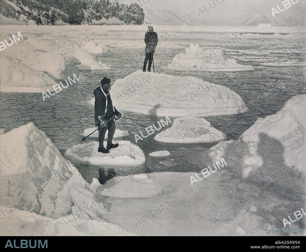 'Campbell and Priestley Afloat on Pancake Ice', 1912, (1913). Expedition members Lieutenant Victor Campbell and geologist Raymond Priestley. The final expedition of British Antarctic explorer Captain Robert Falcon Scott (1868-1912) left London on 1 June 1910 bound for the South Pole. The Terra Nova Expedition, officially the British Antarctic Expedition (1910-1913), included a geologist, a zoologist, a surgeon, a photographer, an engineer, a ski expert, a meteorologist and a physicist among others. Scott wished to continue the scientific work that he had begun when leading the Discovery Expedition to the Antarctic in 1901-04. He also wanted to be the first to reach the geographic South Pole. Scott, accompanied by Dr Edward Wilson, Captain Lawrence Oates, Lieutenant Henry Bowers and Petty Officer Edgar Evans, reached the Pole on 17 January 1912, only to find that the Norwegian expedition under Amundsen had beaten them to their objective by a month. Delayed by blizzards, and running out of supplies, Scott and the remainder of his team died at the end of March. Their bodies and diaries were found eight months later. From Scott's Last Expedition, Volume II. [Smith, Elder & Co., London, 1913].
