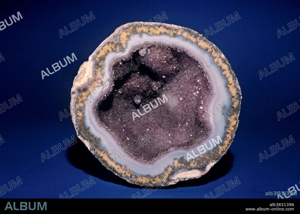 Geodes are roughly spherical objects that form in various geologic environments. One method involves basalts (dark fine grained igneous rocks) typical of lava flows worldwide. Gases dissolved in molten rock (magma) can form bubbles, like the ones we see in carbonated drinks. Rapid cooling of magma traps these bubbles as irregular or rounded cavities, or open spaces, in the basalt. Groundwater may then trickle through the rock and, over time, dissolve silica (silicon oxide) from the rock and re-precipitate the silica in layers on the insides of the cavities. This creates banded agate. A final stage of precipitation may leave a 'druse', or layer of tiny quartz crystals, as a final stage before the water stops flowing. Weathering of the basalt frees these balls of hard silica into the soil, from which they can be collected and split open to reveal the layers inside.