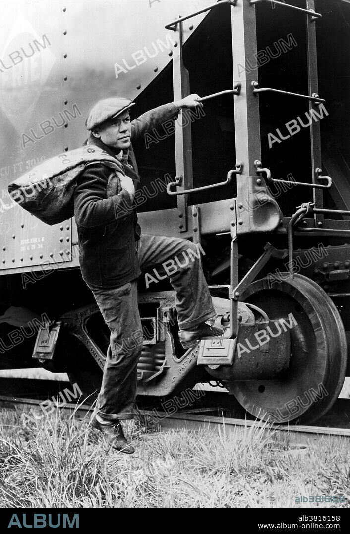 Entitled: "Lou Ambers with a large bag over his shoulder, mounting the ladder of a train car." A hobo is someone who wanders from place to place without a permanent home or a means of livelihood. With the end of the American Civil War in the 1860s, many discharged veterans returning home began hopping freight trains. Others looking for work on the American frontier followed the railways west aboard freight trains in the late 19th century. The number of hobos increased greatly during the Great Depression era of the 1930s. With no work and no prospects at home, many decided to travel for free by freight train and try their luck elsewhere. Photographed by Alan Fisher, 1935.