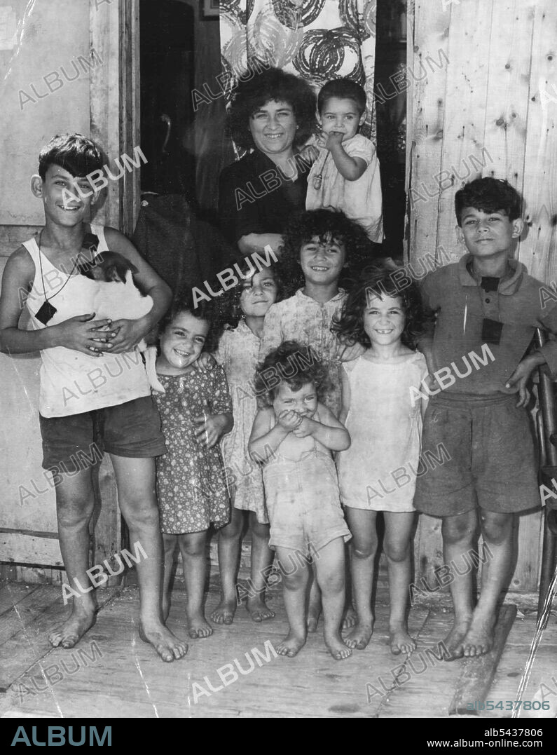 Mrs. Joseph Abela, who arrived with her husband from Malta 1½ months ago, stand with her eight children outside their iron and timber shack at Yarra Bay yesterday. March 12, 1952. (Photo by Wilmot/Fairfax Media).;Mrs. Joseph Abela, who arrived with her husband from Malta 1½ months ago, stand with her eight children outside their iron and timber shack at Yarra Bay yesterday.