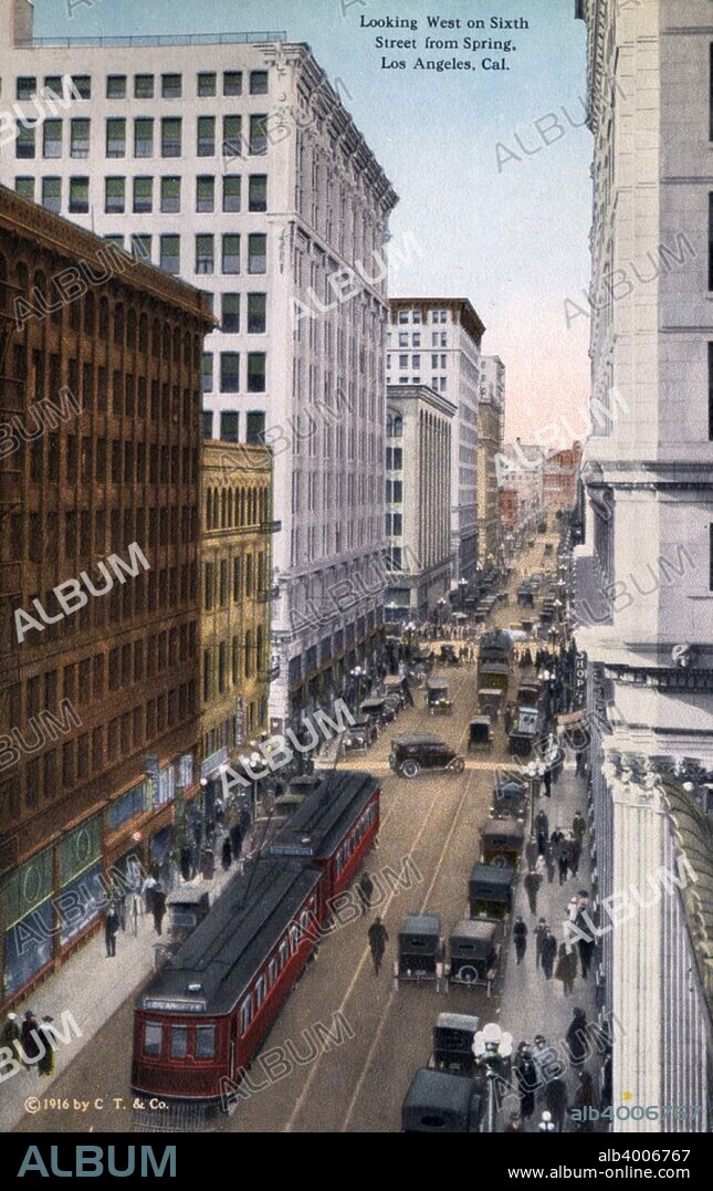 Looking west on 6th Street from Spring Street, Los Angeles, California, USA, 1915. Vintage postcard showing a city street scene. The street is teeming with pedestrians, veteran cars and streetcars.