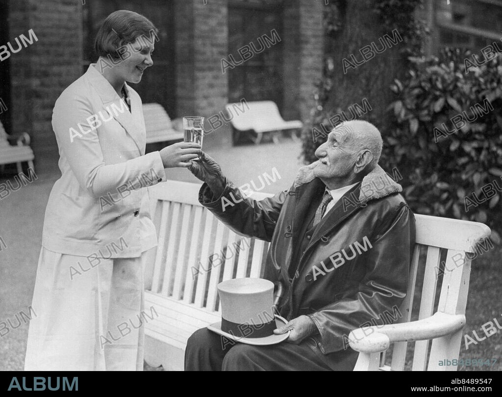 Orig. bildtext... ZARO AGHA AT THE HEALTH SPA. Photo shows: Zaro Aga, the 157-year-old Turk, tries the waters at Harrogate, Yorkshire. Anm. Z Agha, 1774-1934. Cylinderhattar Profiler Skinnjackor Pälskragar Räcka över Ta emot Bänkar Spjälor Leende Kurorter CD523 persons: ZARO AGHA sites: TURKIET*;HARROGATE;STORBRITANNIEN.