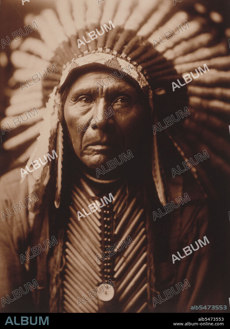 Edward S. Curtis Native American Indians -  Three Horses, head-and-shoulders portrait, facing front, wearing headdress circa 1905.
