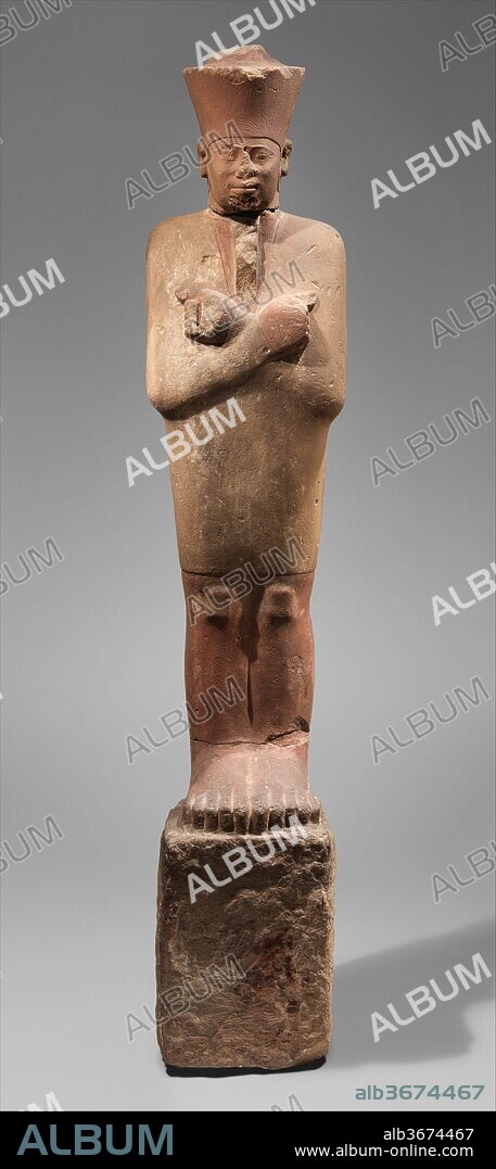 Statue of Nebhepetre Mentuhotep II in the Jubilee Garment. Dimensions: H. 252.9 cm (99 9/16 in.); W. 47.7 cm (18 3/4 in.); D. 43.7 cm (17 3/16 in.). Dynasty: Dynasty 11. Reign: reign of Mentuhotep II. Date: ca. 2051-2000 B.C..
Twenty two statues of this type stood beside (but not in the shadow of) sycomore and tamarisk trees that lined the processional path through the forecourt of the mortuary temple of Mentuhotep II at Deir el-Bahri. The rough, rectangular base was inserted into the ground.  The king wears the traditional short mantle of the pharaoh's thirty-year jubilee festival (Heb Sed). In his fists were the now missing scepter and flail of Egyptian kings and the god Osiris, probably made of metal. The head on this piece wears the "red" crown of Lower Egypt.  No head with the "white" crown of Upper Egypt was found; but it is conceivable that the statues along the south side of the path wore the "white" Upper Egyptian crown, the ones along the north side the "red" Lower Egyptian one.  At some later time all statues from the forecourt were decapitated and broken up.  Some bodies were buried close to their original places, others were moved around. Most heads are missing.  Both the body and head of the Museum's statue were found in the  area of the temple of Hatshepsut that is adjacent to the Mentuhotep temple. It is not certain that the head really belonged to this particular body.
The style of the statue is intentionally archaic, presumably because Mentuhotep  II is commemorated as the ruler who reunified the country after the First Intermediate Period and thus restored Egypt to its original state first created during the late Predynastic and early Dynastic Period.