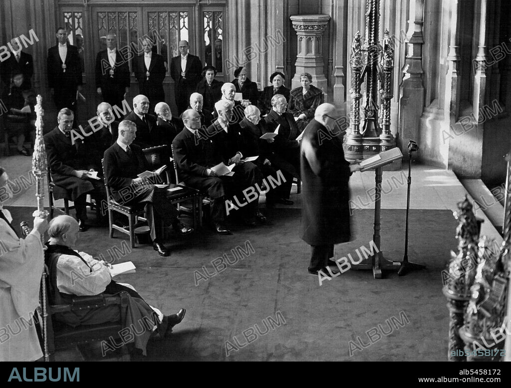 Churchill Unveills Memorial Window in Westminster Hall - The Scene in Westminster Hall during Mr Churchill's speech after the dedication. On left is Dr. Fisher, the Archbishop of Canterbury. Seated behind Mr Churchill are (front row, left to right): The Duke of Wellington, Lord Simons, Mr. W.S. Morrison (Speaker), Mr. C. Attlee. The Marquis of Salisbury. (Back row, left to right):- Rt. Hon David Ecoles, Rt. Hon Clement Davies, Lord Milner, Sir Ninian Comper, Viscount Samuel, The Marquiis of Cholmondeley. The ladies (at right) are, left to right: Mrs Morrison, Mrs Churchill, Mrs Davies and Mrs Attlee.
The Prime Minister Mr Churchill unveiled, and Dr. Fisher the Archbishop of Canterbury dedicated the new great South window in Westminster Hall, designed by Sir Ninian Comper as a memorial to the 57 member and servants of both Houses of Parliament who died in World War II. November 12, 1952. (Photo by  Fox Photos).