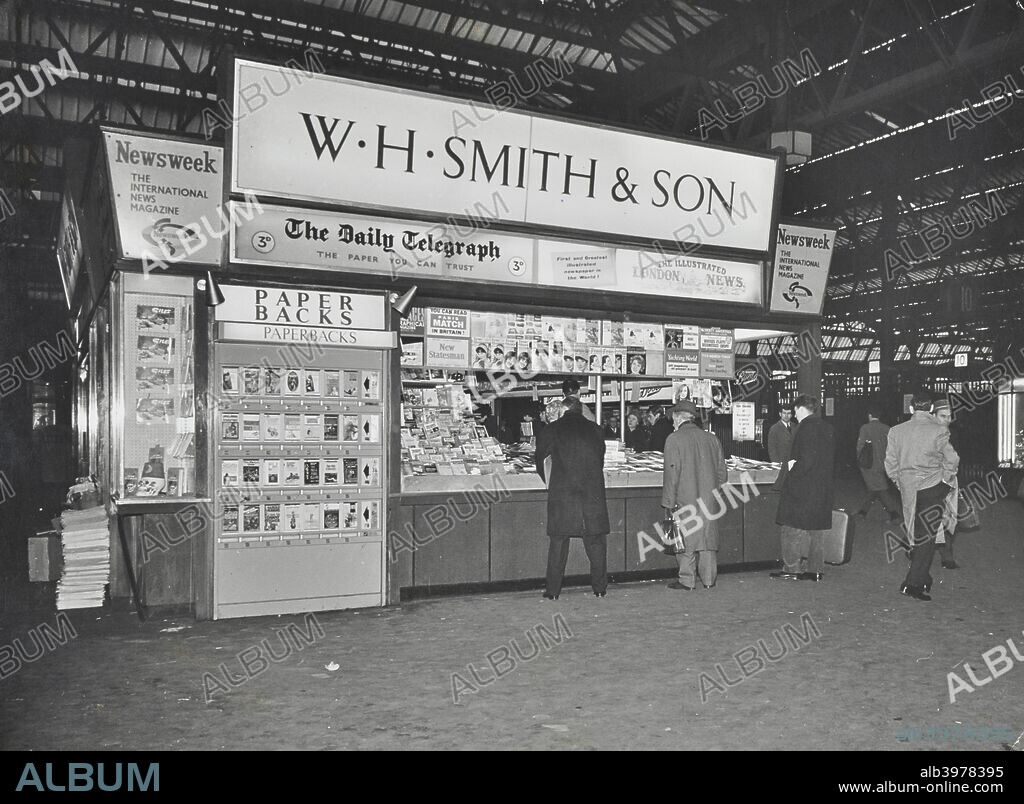 WH Smith's bookstall at Waterloo Station, Lambeth, London, 1960. Bookstall on the station concourse, selling newspapers and magazines. Men wait at the counter to be served.
