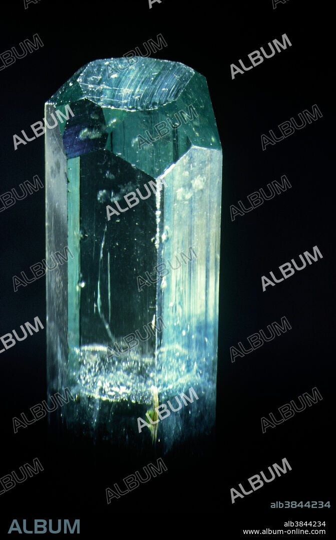 Beryl is composed of beryllium aluminum silicate and is the chief ore of the element beryllium. Crystals of beryl in certain unique rocks called pegmatites can be as large as railroad boxcars. These immense crystals are never transparent, but some pegmatites contain smaller, well formed and transparent beryl crystals; these occur in various colors, and each variety used as a gemstone has its own special name. The blue or blue-green variety is called aquamarine. Large fine aquamarines occur in Brazil, Nigeria, Namibia, Madagascar and many other places. The hexagonal (6-sided) symmetry of the mineral is evident in this excellent and gemmy crystal from a place called Kleine Spitzkopje in Namibia (South West Africa).