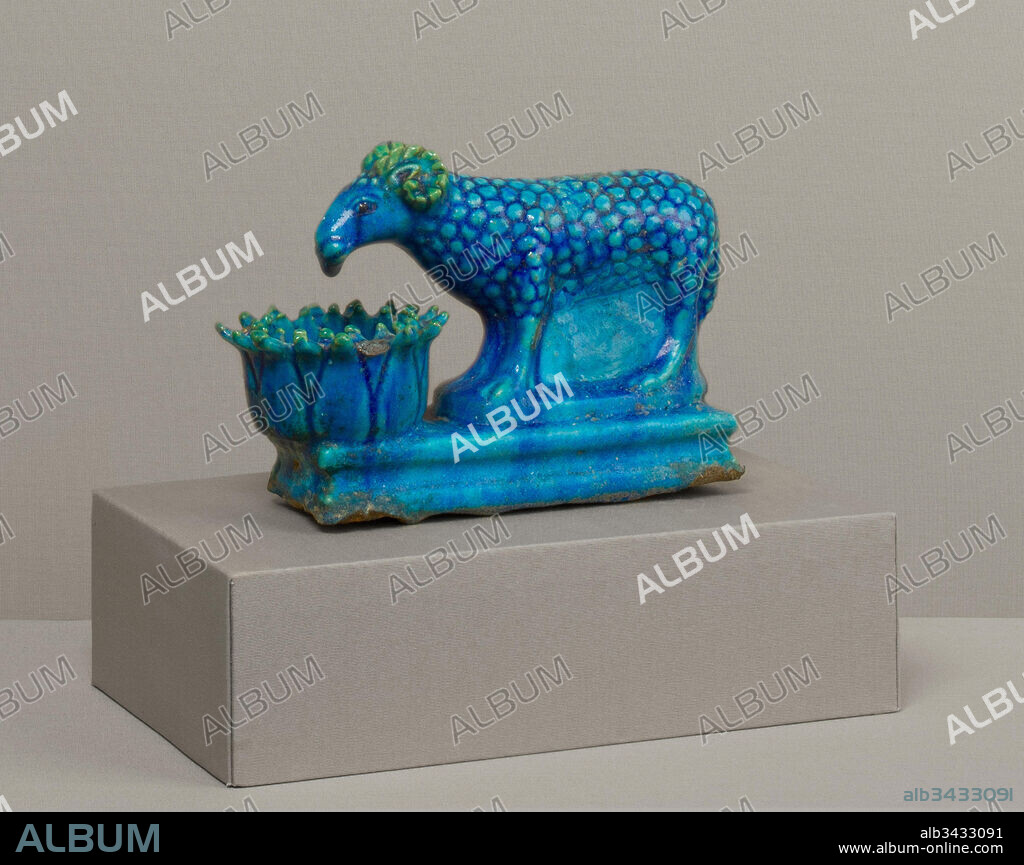 Ram with lotus-shaped manger, Roman Period, A.D. 2nd century, From Egypt; Said to be from Fayum, Medinet el-Fayum (Krokodilopolis-Arsinoe), Faience, L. 17 cm.; H. 12 cm., This charming ram, with its almost prehensile muzzle, feeds from a lotus-form trough. The traditional Egyptian gods Amun or Khnum were identified with curly-horned rams, but by this time several other divinities were as well.