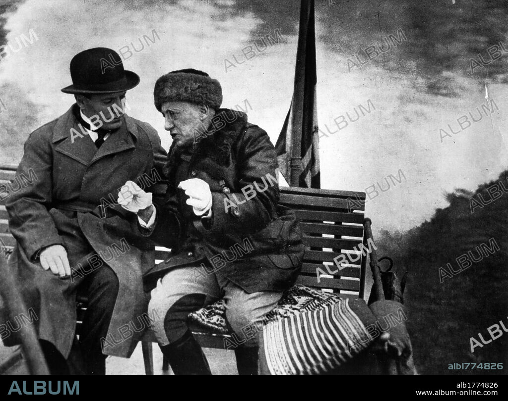 Gabriele D'Annunzio with Benito Mussolini. In the garden of Cargnacco Villa (the Vittoriale) Gabriele D'Annunzio, Italian poet and writer, speaking with Benito Mussolini on a bench. Gardone Riviera, May 1925.