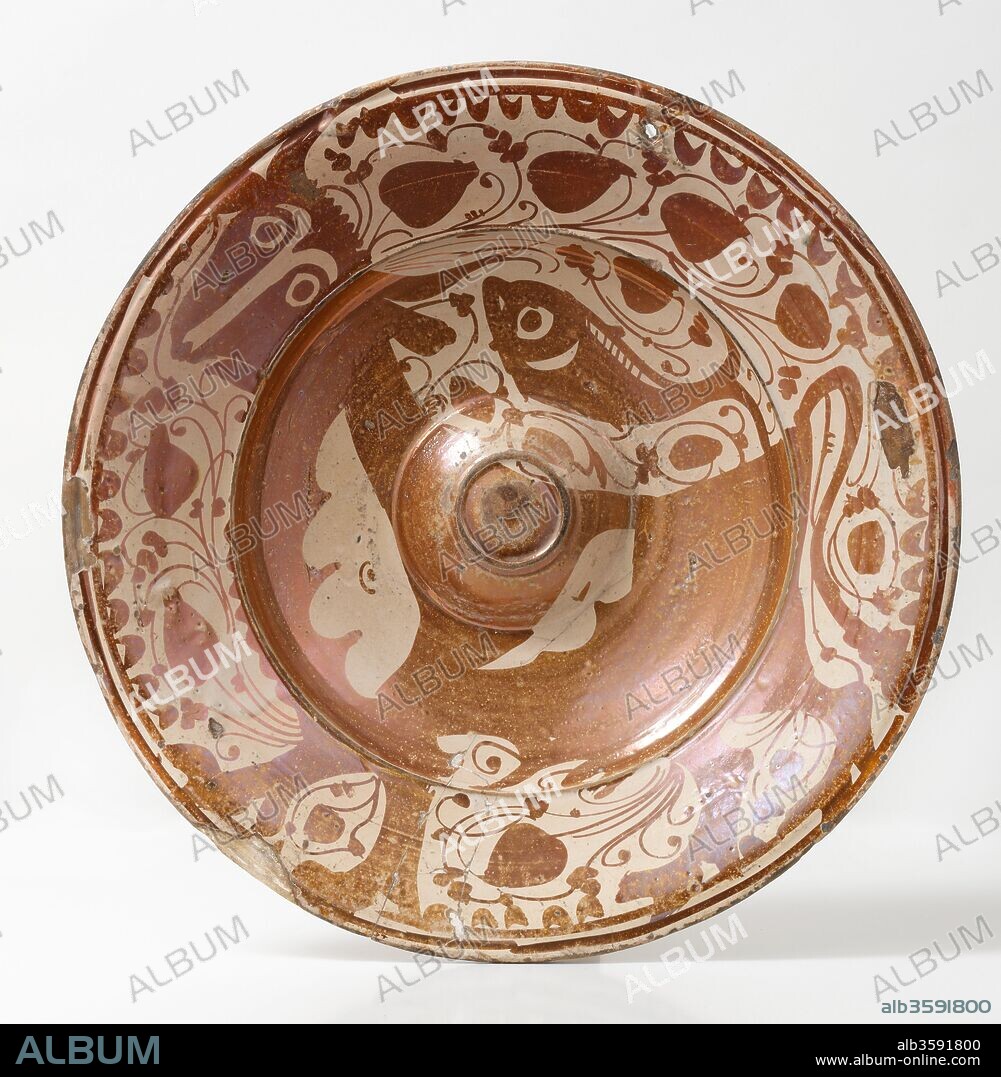 Fuente (recipiente), Siglo XVII, Cerámica (loza decorada con reflejos metálicos, umbo central y la figura de un pez que descansa sobre el lomo de un toro, rodeado de hojas acorazonadas y cenefa de la ungla (uña)), de Manises o Valencia (Valencia), Diámetro: 40,3 cm.