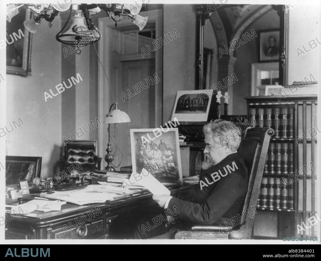 FRANCES BENJAMIN JOHNSTON. John Willock Noble, 1831-1912, between c1890 and c1910. Three-quarter length portrait, seated at desk, left profile. [Politician, lawyer, brigadier general in the Civil War. Note framed photograph of Native Americans on desk. 'Under his watch as Secretary of the Interior, the Cherokee Commission negotiated eleven agreements that removed nineteen indigenous tribes to small allotments in the Oklahoma Territory, while opening the land to homesteaders'].