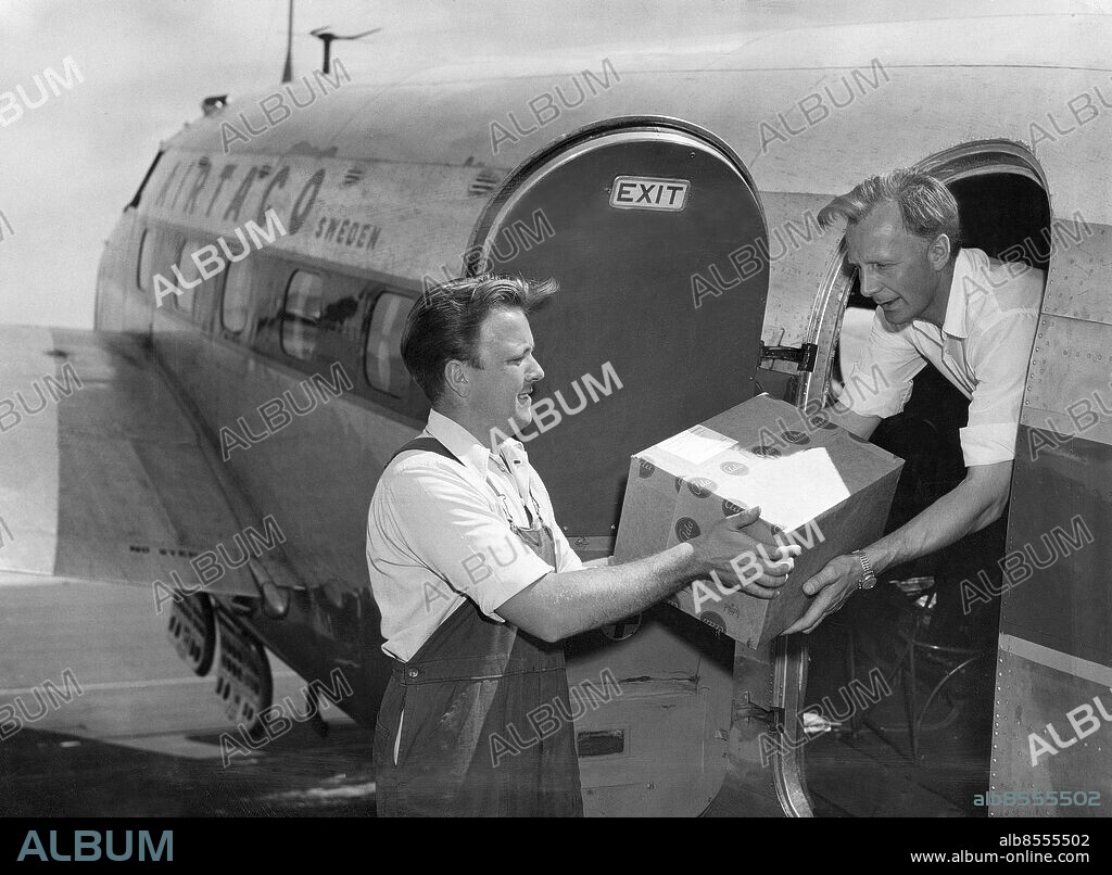 STOCKHOLM 1953-06-29. Flygkapten Torvald Andersson (th) lastar Expressens tidningsplan, en Lockheed Lodestar, med apoteksvaror, Arne Elfving hos Apotekarnas Droghandel hjälper till. Apoteket Gripen i Sundsvall har kontaktat Apotekarnas droghandel i Stockholm med en begäran om antibiotika som kan sättas in mot paratyfus.. Foto: Jonny Graan / EXP / TT / Kod: 16. **AFTONBLADET OUT**.