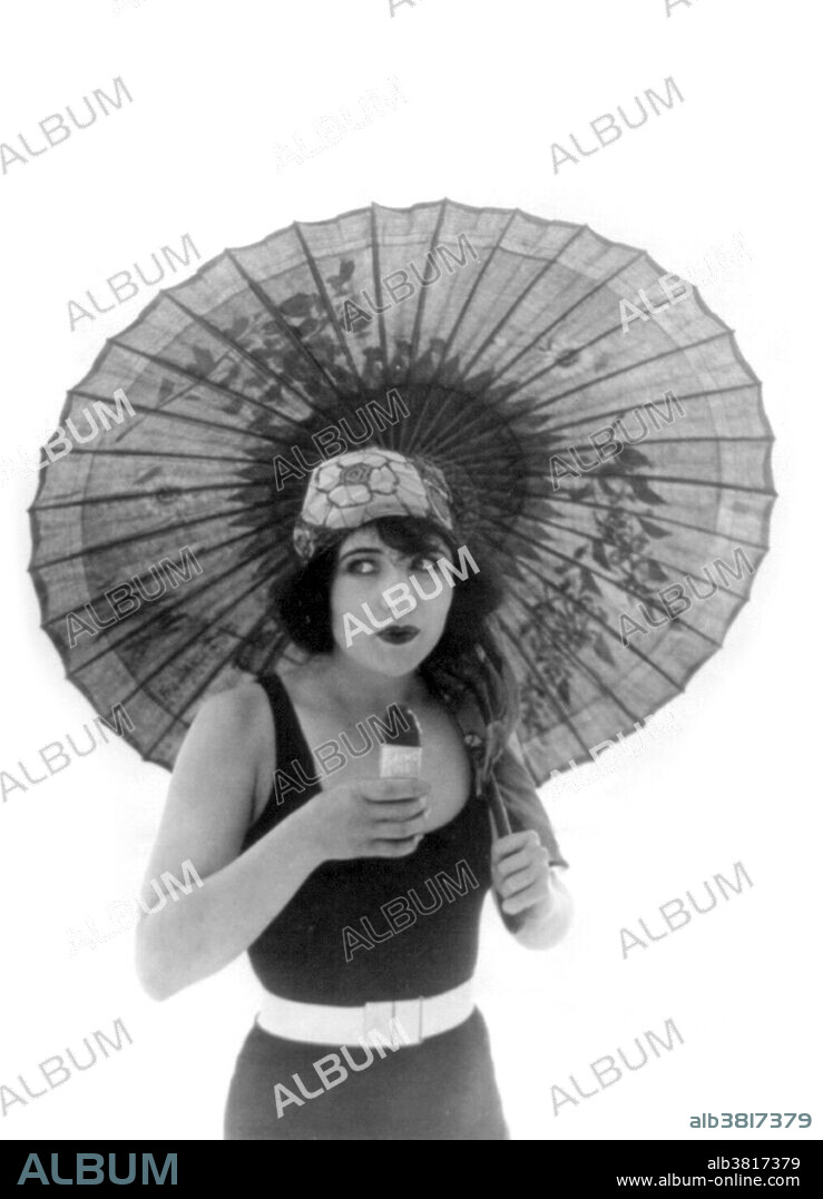 Entitled: "Betty Compson with umbrella, in bathing suit, facing slightly right, eating Eskimo Pie." Betty Compson (March 19, 1897 - April 18, 1974) was an American actress and film producer. Most famous in silent films and early talkies, she is best known in her performances in The Docks of New York and The Barker, the latter earning a nomination for the Academy Award for Best Actress. Her popularity allowed her to have creative control over her films as she was also able to produce. After retiring from the screen in 1948, she began a cosmetic line and helped her husband run a business called "Ashtrays Unlimited". She died in 1974, of a heart attack, at the age of 77.  Photographed by E.D. Leshin, December 26, 1922.