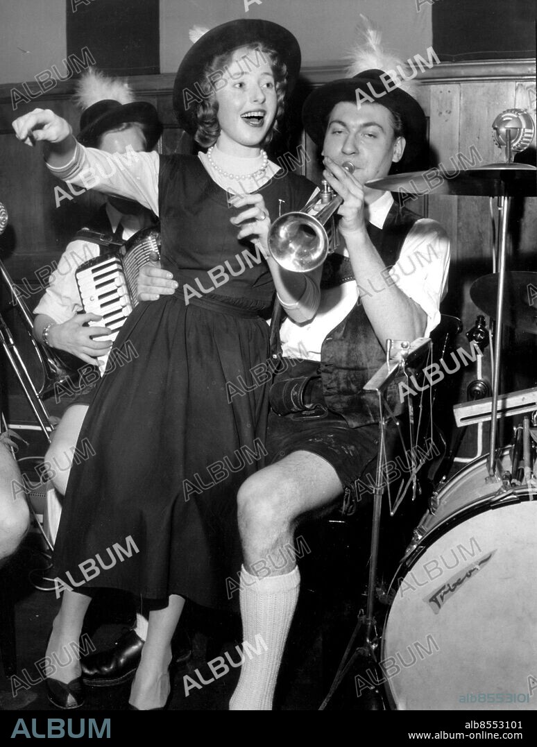 19570205 - Restaurang Kvarnen på Tjärhovsgatan i Stockholm har börjat med äkta tyrolermusik. "Dirigenten" hämtas ur publiken (Helga Eriksson) och hamnade vid detta tillfälle i knät på trumpetaren Günther. Kvarnen är den restaurangen på Söder som har underhållning. Foto: Carl Erik Sundström Kod. 59 . COPYRIGHT SCANPIX SWEDEN.
