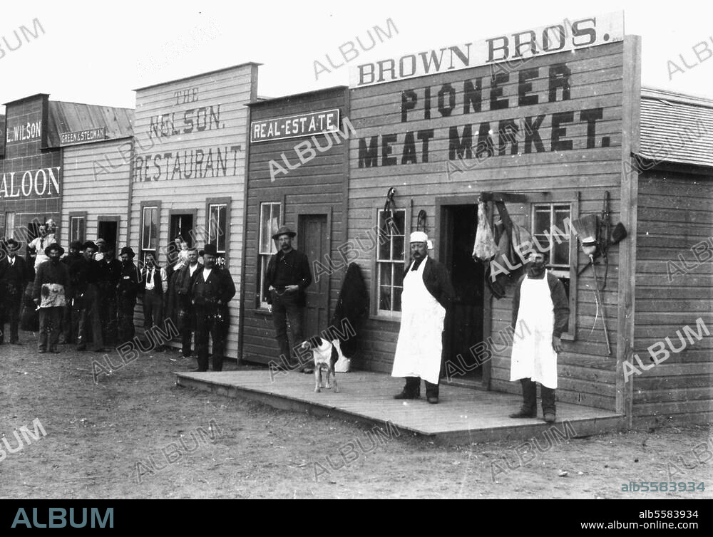 Geschichte der USA, "Wilder Westen". Blick auf Läden sowie Restaurant und Saloon in der Broadway Street von Round Pond in Oklahoma: Inhaber und Kunden posieren für den Fotografen. Foto, Januar 1894.