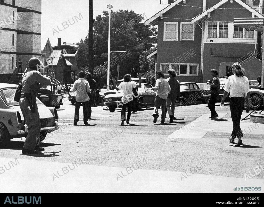 Berkeley, California:  May 15, 1969 A policeman shooting demonstrators in the back on 'Bloody Thursday' at People's Park riots. Police pursued the retreating protestors, firing tear gas and buckshot.