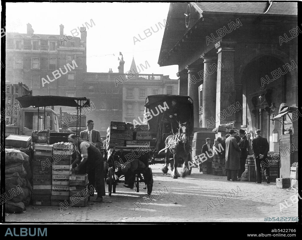 CHARLES WILLIAM PRICKETT. Covent Garden, City of Westminster, Greater London Authority, 1930s. Market traders setting up the fruit and vegetable market at Covent Garden outside St Paul's Church, with a horse-drawn cart driving through the market.