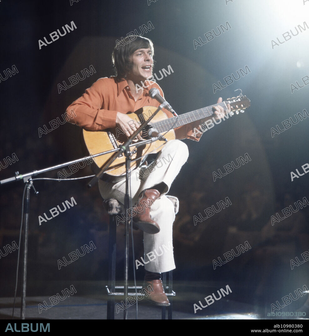 The German musician and well-known representative of the singer-songwriter scene Reinhard Mey plays with his guitar at a TV gig, Germany 1970s.