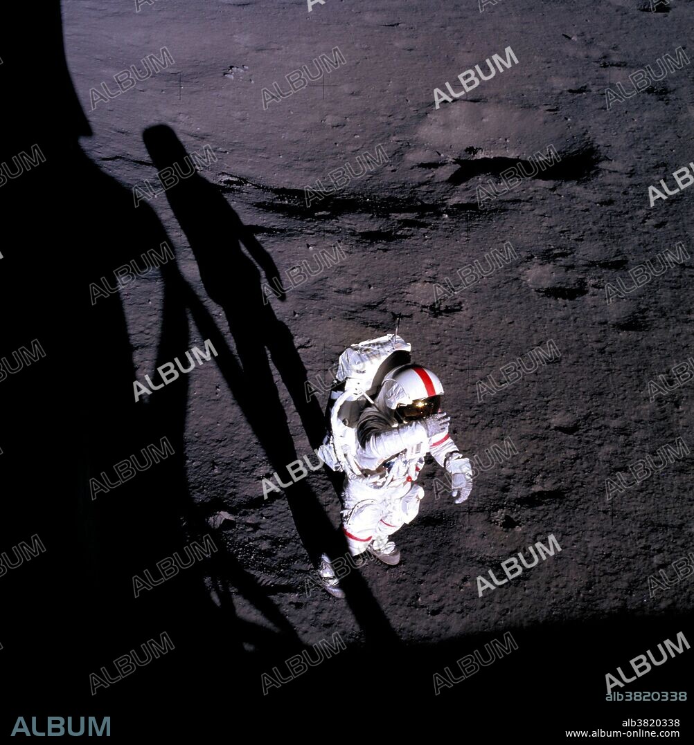 Astronaut Alan B. Shepard Jr., commander, holds his right glove over his helmet visor, apparently shading his eyes from the brilliant sun. This photo was taken by astronaut Edgar D. Mitchell, lunar module pilot, through the window of the Lunar Module (LM) on February 5, 1971. Shepard and Mitchell descended in the LM to explore the moon, while astronaut Stuart A. Roosa, command module pilot, remained with the Command and Service Modules (CSM) in lunar orbit. This photograph was taken during the first of two extravehicular activities (EVA).