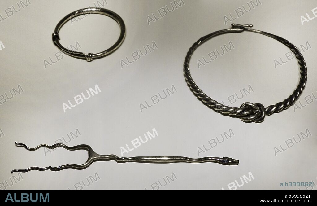 Cultura Ibérica. Objetos de uso litúrgico. Brazalete, torques y, en primer término, fuscícula o tenedor. Utilizados por los sacerdotes u oficiantes en las ceremonias religiosas. Siglos II-I a. C. Plata. Procedente de Mengíbar y de la provincia de Jaén (Andalucía). Museo Arqueológico Nacional. Madrid. España.