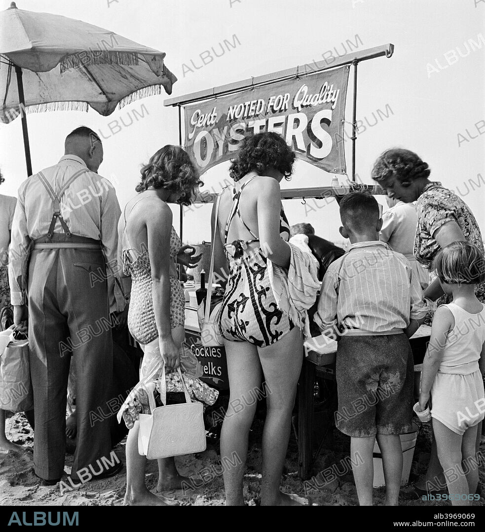 Holidaymakers crowd around a stall on the beach selling ready to eat seafood, Blackpool, c1946-c1955.