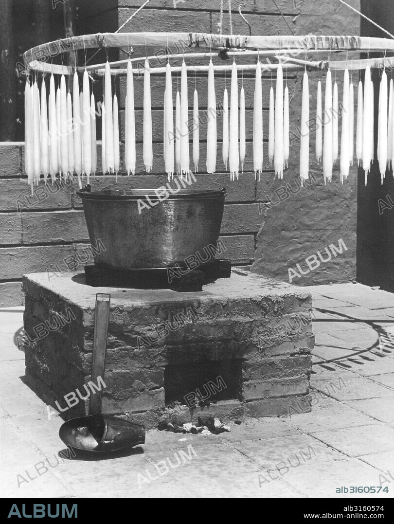 California: c. 1930 The padres tought the Native Americans how to make candles. Here they are hanging after they have been dipped.