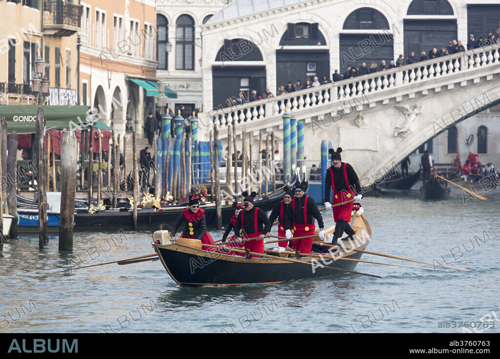 People in Mickey Mouse Venice Carnival costumes, rowing gondola on Grand Canal by Rialto Bridge, Venice, UNESCO World Heritage Site, Veneto, Italy, Europe.