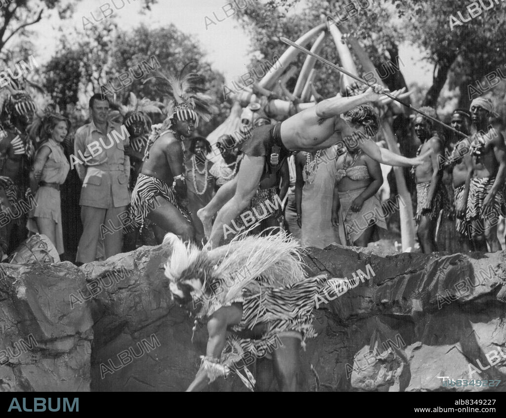 Gordon (Tarzan) Scott and Witch Doctor Jester Harrison are thrown into the lion pit by Sukulu warriors as the United Nations Medical team of Peter Van Eyck and Vera Miles await their turn in a scene from "Tarzan's Hidden Jungle" produced by Sol Lesser and distributed by RKO Radio. October 14, 1955.