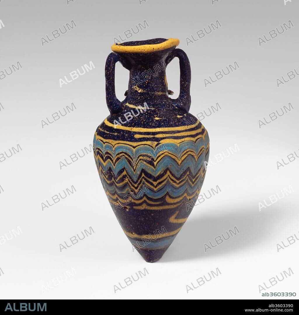 Glass amphoriskos (perfume bottle). Culture: Greek, Eastern Mediterranean. Dimensions: H. 3 9/16 in. (9 cm). Date: late 6th-5th century B.C..
Translucent dark cobalt blue, with handles in same color; trails in opaque yellow and opaque turquoise blue.
Broad inward-sloping rim-disk; cylindrical neck, expanding slightly downwards; broad, angular shoulder; tall conical body, tapering downwards to pointed bottom; two vertical strap handles applied to top of shoulder, drawn up, and pressed onto underside of rim-disk.
One yellow trail attached at edge of rim-disk; another yellow trail applied to neck and wound in a spiral across shoulder and around top of body, then tooled into an uneven zigzag pattern on upper half of body, where a turquoise blue trail is added, mingling with the yellow; below this, both trails drawn down and wound horizontally once around lower body.
Complete, except for base-knob; parts of trails completely weathered, leaving only indentation in body; dulling, pitting, and faint iridescence.