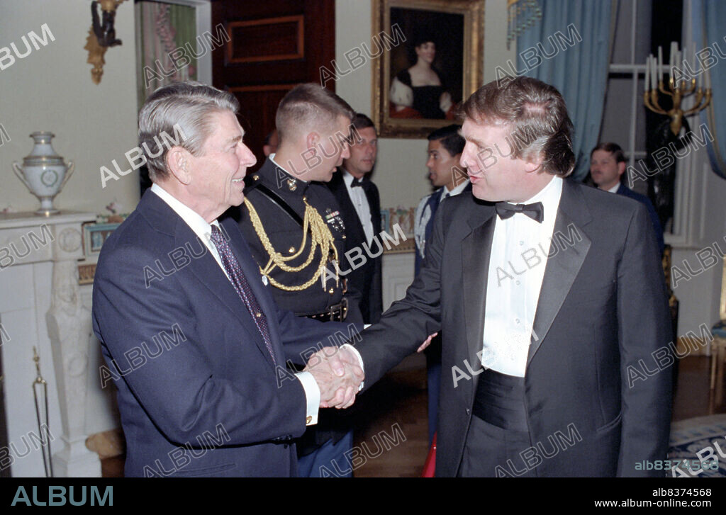 President Ronald Reagan shakes hands with Donald Trump at a reception for members of the ""Friends of Art and Preservation in Embassies"" Foundation in the White House's Blue Room, Washington, DC, 11/3/1987.