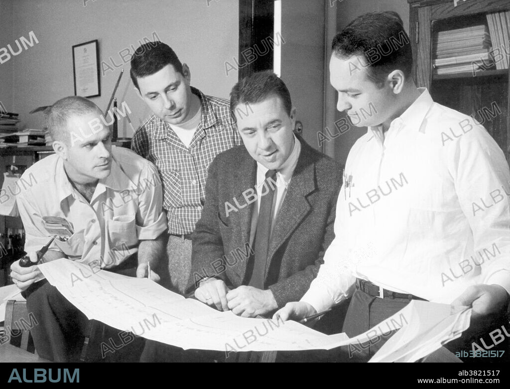 Space scientist Dr. James Alfred Van Allen (1914-2006), surrounded by associates at the State University of Iowa. Dr. Van Allen is credited with confirming the existence of radiation belts. The most important discovery of the 1957-58 International Geophysical Year was acknowledged to be the discovery of zones of trapped radiation--protons and electrons---surrounding Earth. Van Allen and his group interpreted data from Geiger counters placed on board the first Explorer satellites.