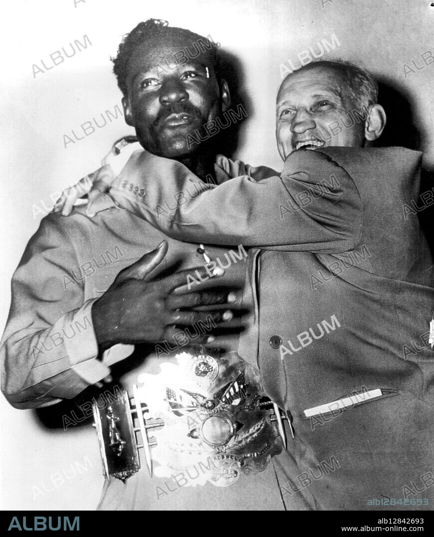 Manager Hugs His New Champ -- Ezzard Charles (left), newly-crowned NBA world heavyweight champion, is embraced by Jake Mintz, his manager, today after receiving the Police Gazette's heavyweight championship belt at ceremonies in downtown hotel. Charles defeated Jersey Joe Walcott on a decision in their 15-round bout at Comiskey Park last night. Charles is wearing the belt. June 23, 1949. (Photo by AP Wirephoto).