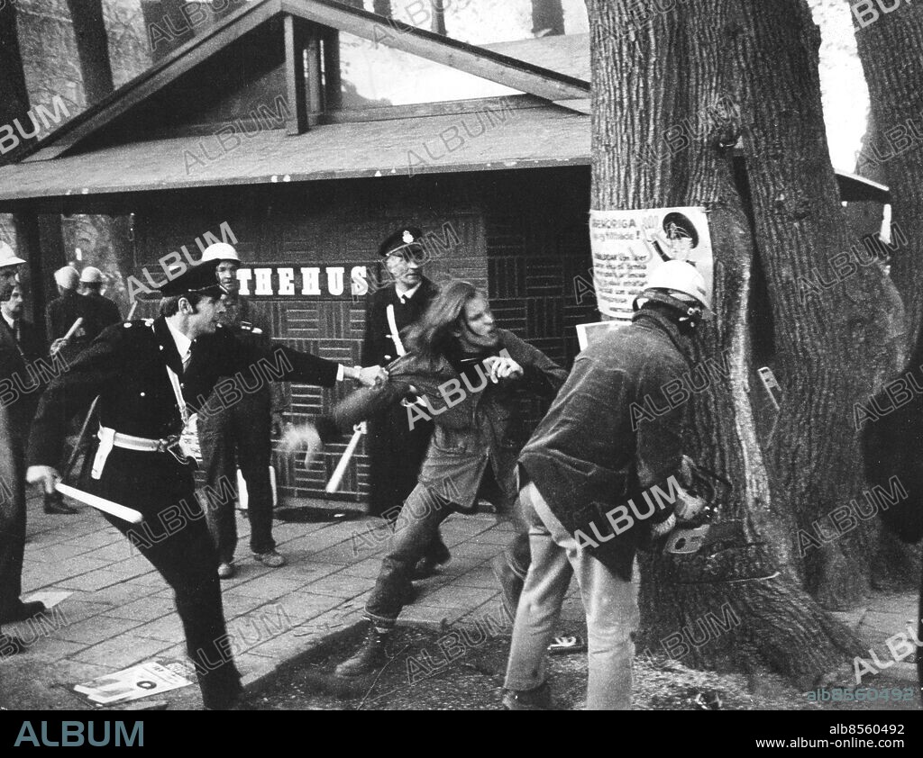 ©SCANPIX SWEDEN, 1971-05.. Demonstration för att rädda almarna i Kungsträdgården, Stockholm. Bilden visar demonstranter i handgemän med poliser vid Thehuset. Affischer sätts upp på ett träd.. Foto: Scanpix. Code: 20360 . ***. ENGCAP: Demostration against that fell elms in Kungsträdgården in Stockholm.