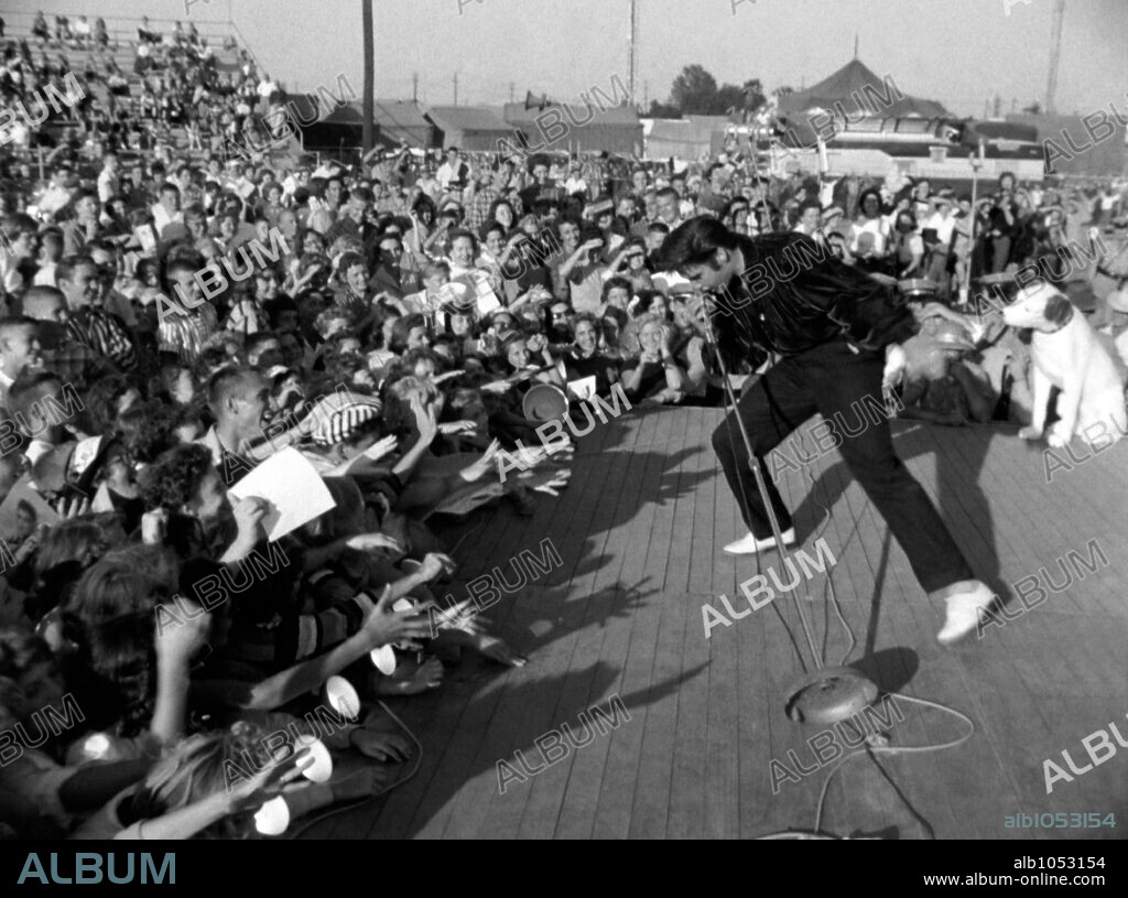 The American singer Elvis Presley performing for a large crowd of fans in 1957.